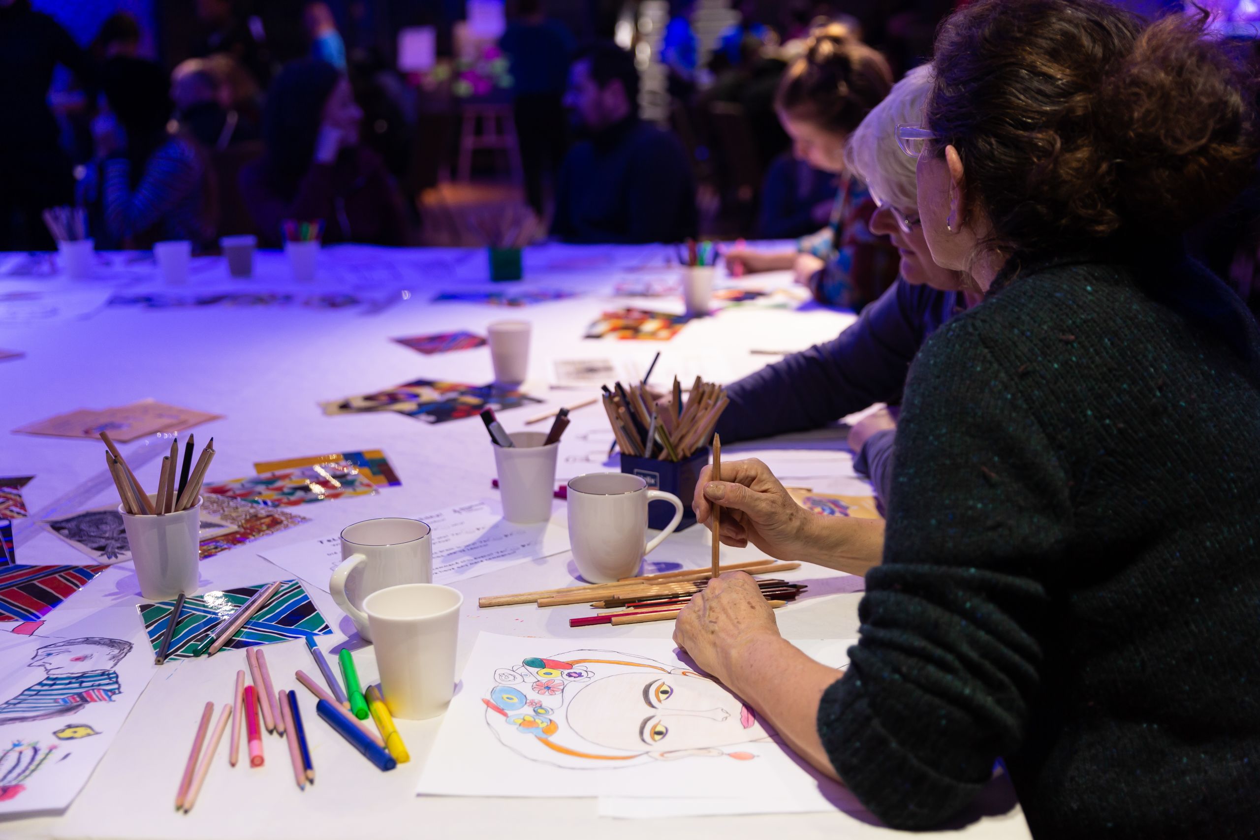 Two people drawing with coloured pencils