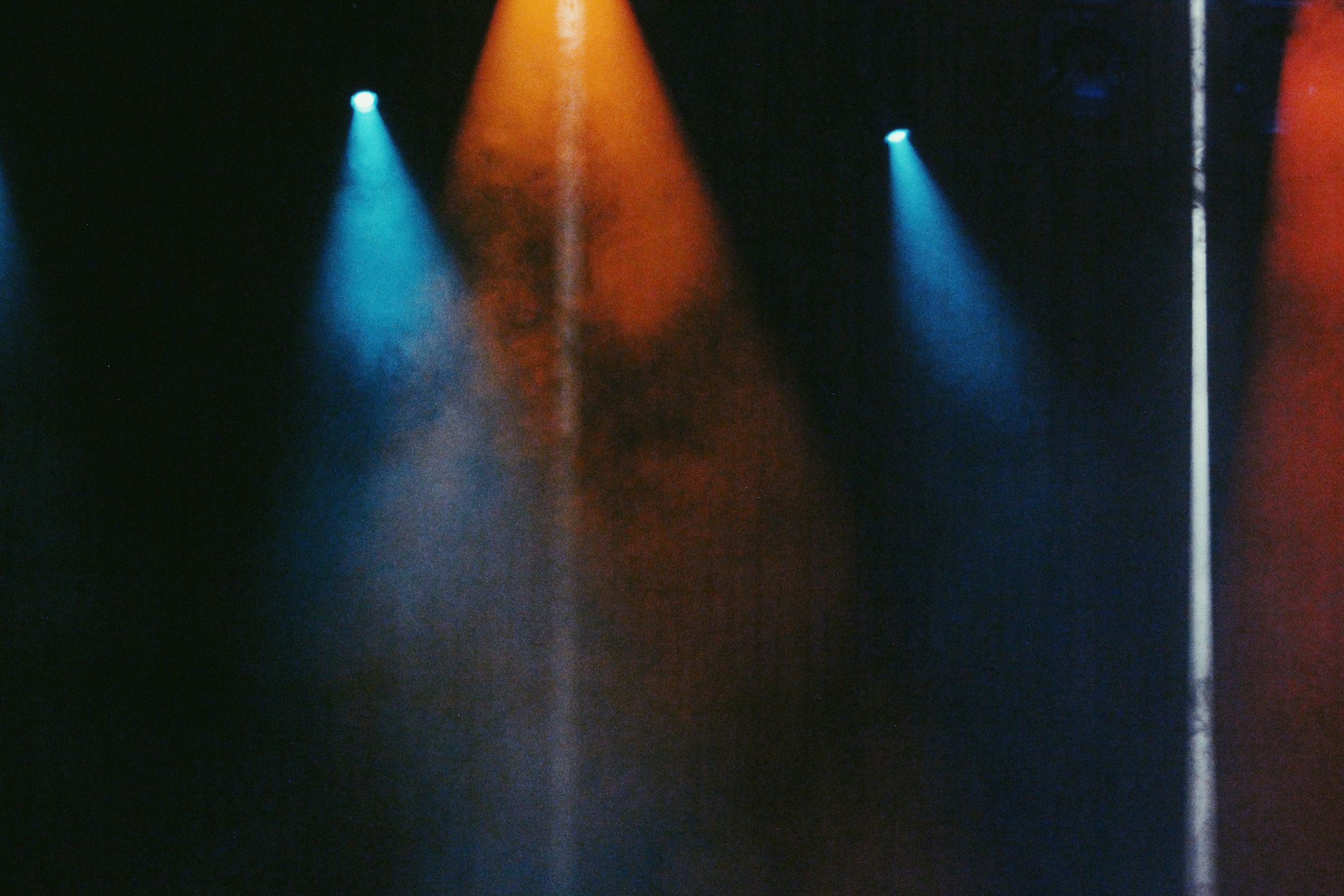 abstract photo of orange and blue lights in a concert room