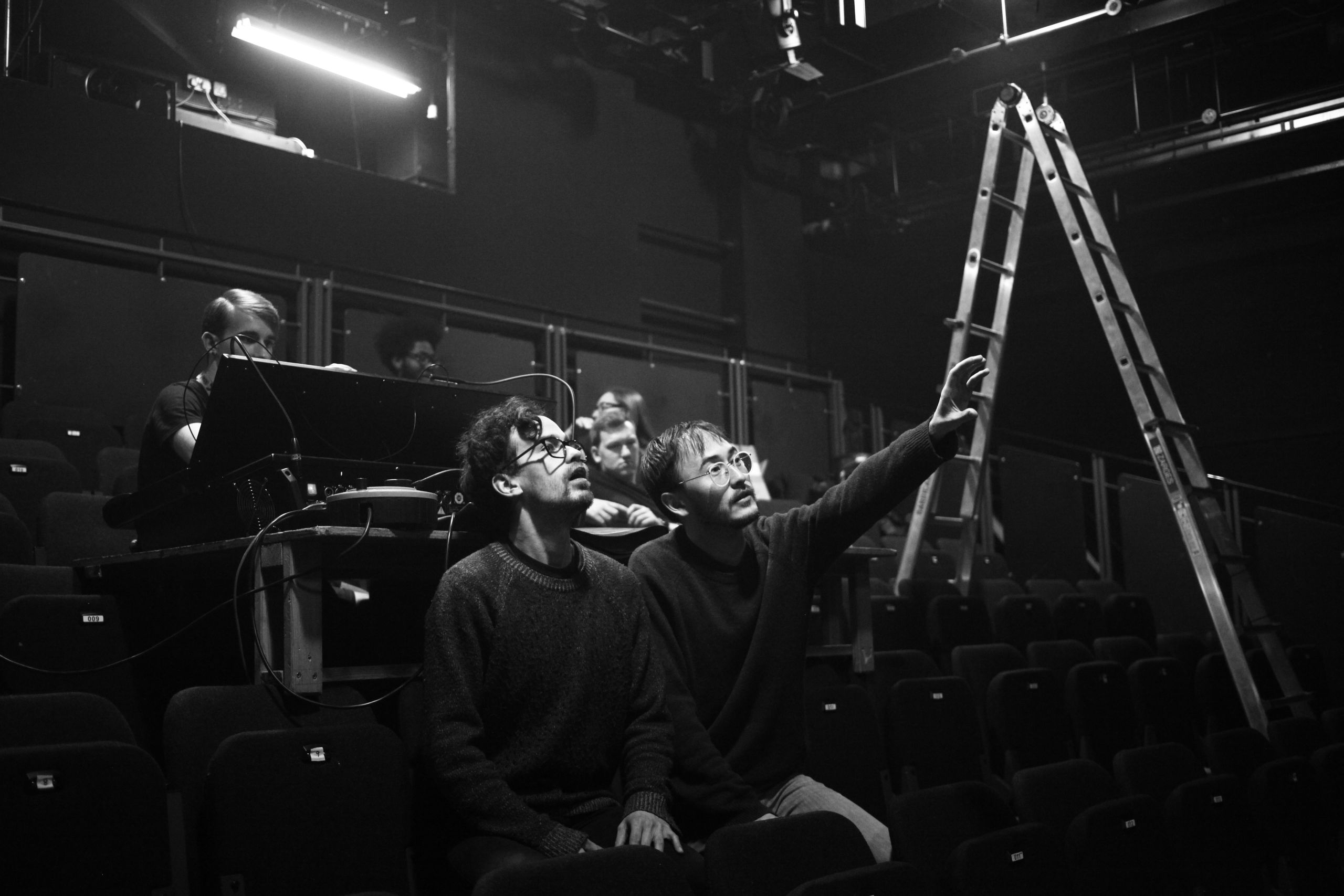 a group of men in a rehearsal room looking at something on the ceiling