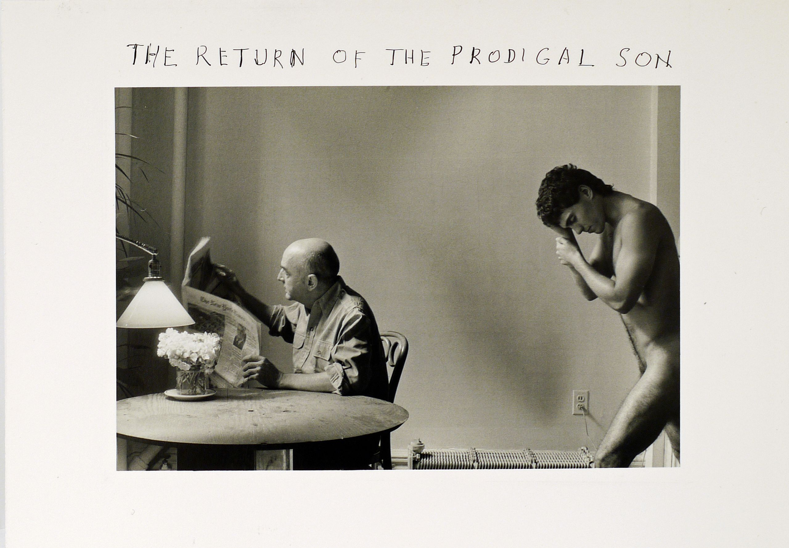 A black and white photo of a naked young man, humbly entering a room where his father, unaware of his son's presence, sits reading a newspaper.