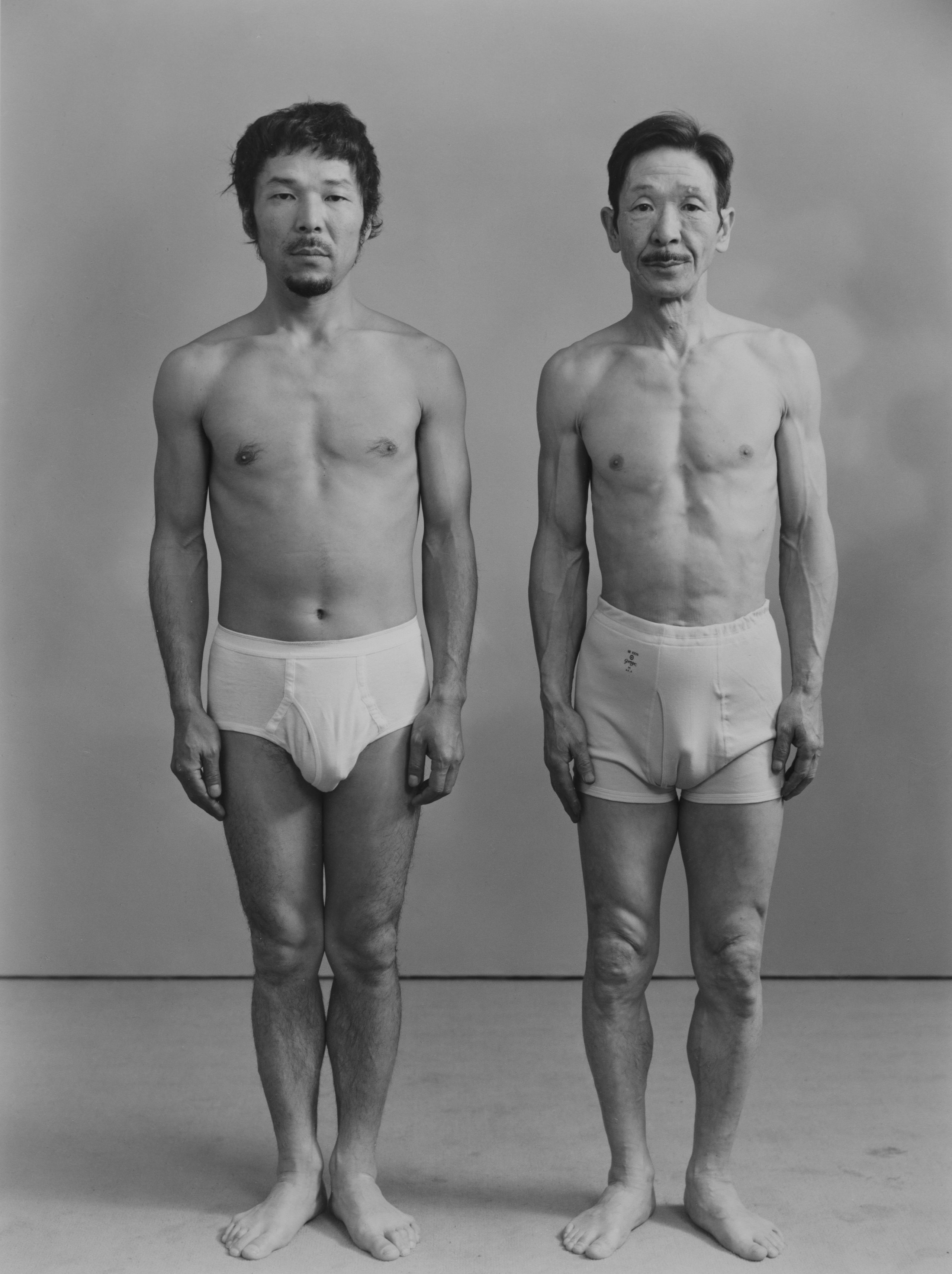 Two men in white underwear stand next to each other facing the camera