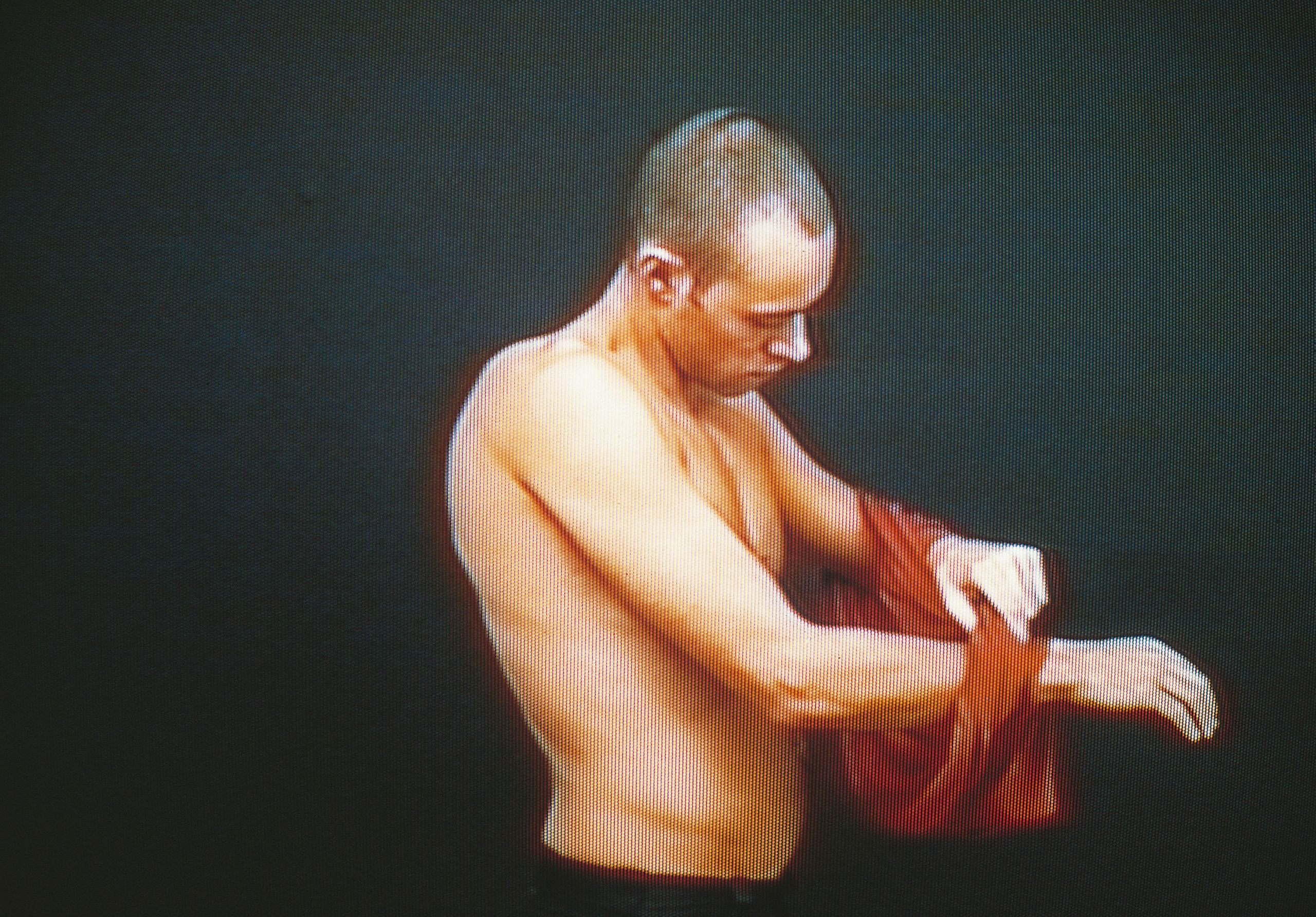 A screenshot of a man taking off an orange t-shirt