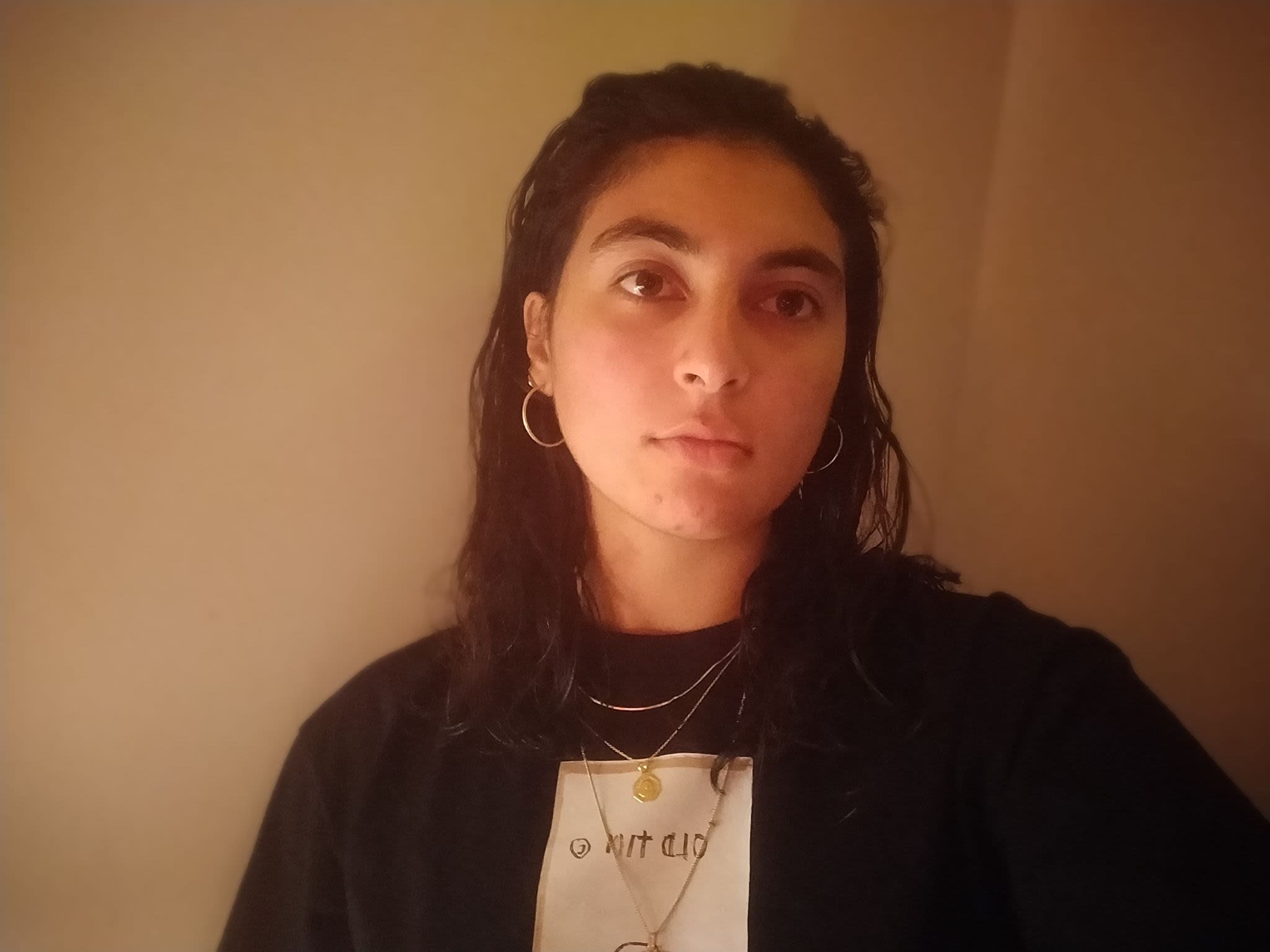 a young woman wearing a black hoodie stares into the distance