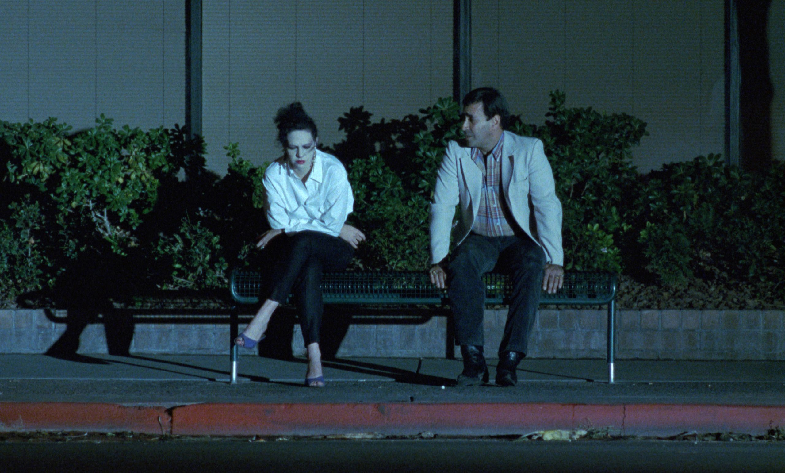 photo of a woman and man sitting at dusk on a bench in the city