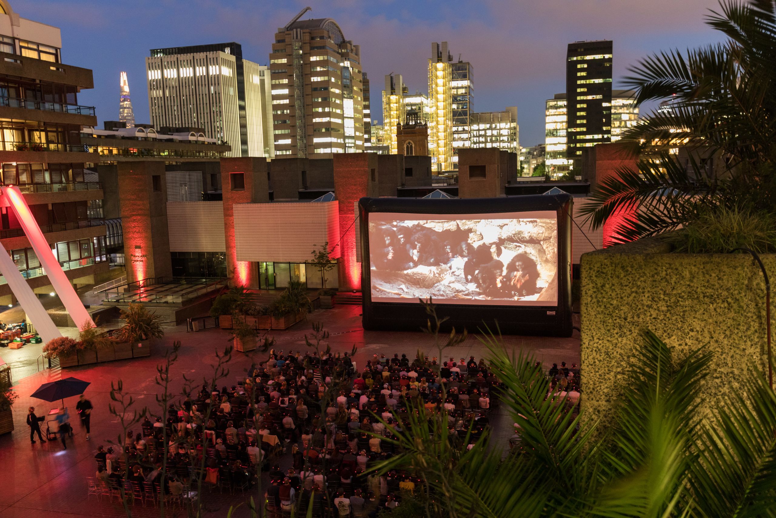 Audience watching a film on the Barbican Sculpture Court